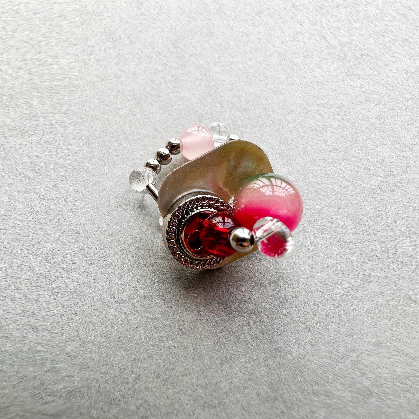 Oblique side view of handmade ring made of seashell, colored glaze, natural stone